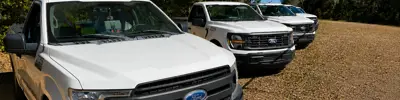 Image of 4 white code compliance trucks lined up outside
